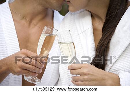 Stock Photo - Woman and a man celebrating with champagne and being affectionate . Fotosearch