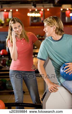 Teenage boy and girl in a bowling alley, girl on her mobile phone View Large Photo Image Picture - Teenage boy and girl in a bowling alley, girl on her mobile phone. Fotosearch