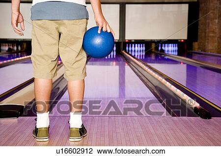 Teenage boy in a bowling alley, holding a blue bowling ball View Large Photo Image Stock Image - Teenage boy in a bowling alley, holding a blue bowling ball. Fotosearch
