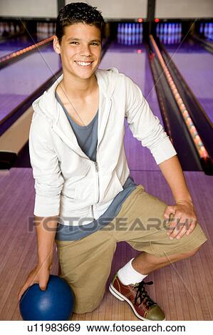 Teenage boy in a bowling alley, holding a blue bowling ball View Large Photo Image Stock Photo - Teenage boy in a bowling alley, holding a blue bowling ball. Fotosearch