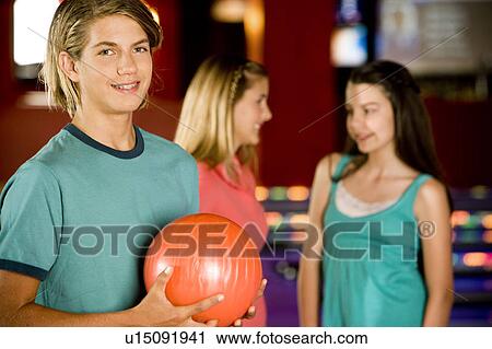 Teenage boy in a bowling alley, two girls in the background View Large Photo Image Stock Image - Teenage boy in a bowling alley, two girls in the background. Fotosearch