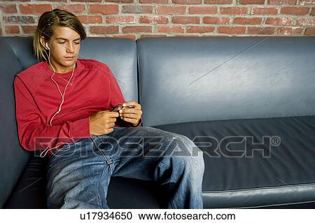 Teenage boy on a seat listening to music on mp3 View Large Photo Image Stock Image - Teenage boy on a seat listening to music on mp3. Fotosearch
