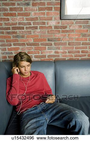 Stock Photograph - Teenage boy on a seat listening to music on mp3. Fotosearch