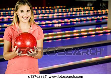 Teenage girl in bowling alley holding a red bowling ball View Large Photo Image Stock Photo - Teenage girl in bowling alley holding a red bowling ball. Fotosearch