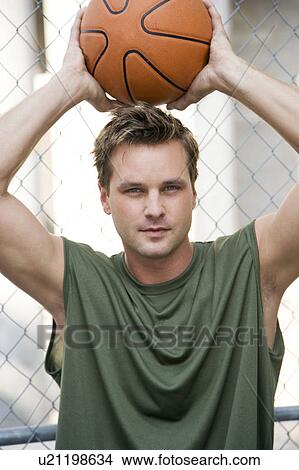 Man in a green vest holding a basketball above his head. View Large Photo Image Picture - Man in a green vest holding a basketball above his head.. Fotosearch