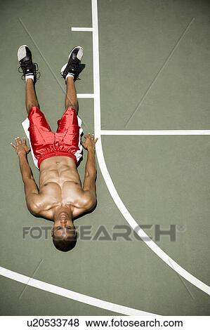 Stock Photo - Man laying down on an outdoor basketball court . Fotosearch