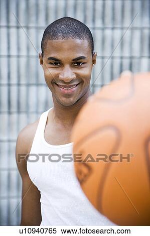 Stock Photography - Portrait of a smiling young African American man holding a basketball. . Fotosearch