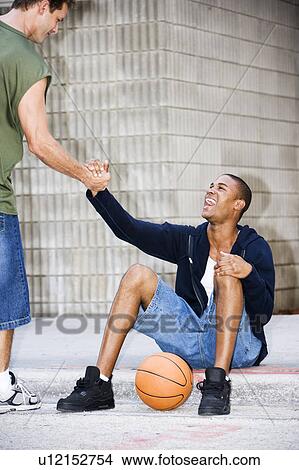 Picture - Portrait of a young African American man sitting greeting his friend. Fotosearch