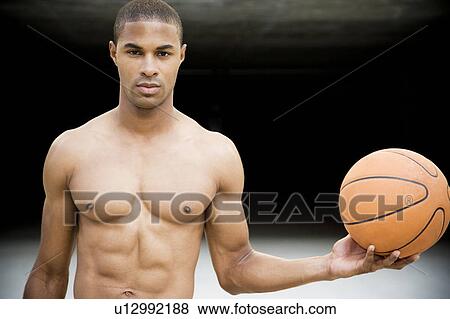 Stock Photo - Portrait of a young African American man holding a basketball. . Fotosearch