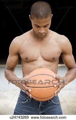Stock Photo - Portrait of a young African American man holding a basketball. . Fotosearch