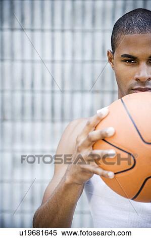 Stock Photography - Portrait of a young African American man holding a basketball. . Fotosearch