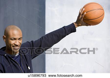 Portrait of young African American man holding a basketball arm outstretched View Large Photo Image Stock Image - Portrait of young African American man holding a basketball arm outstretched . Fotosearch