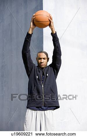 Portrait of young African American man holding a basketball above his head View Large Photo Image Stock Image - Portrait of young African American man holding a basketball above his head. Fotosearch