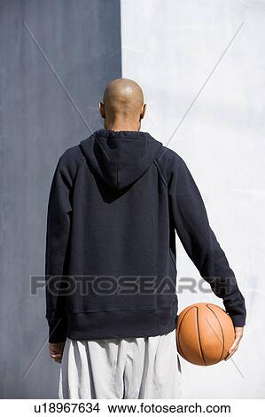 Picture - Rear view portrait of young African American man holding a basketball. Fotosearch