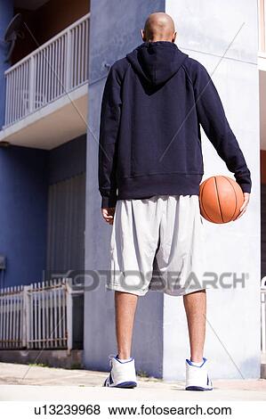 Stock Photo - Rear view portrait of young African American man holding a basketball. Fotosearch