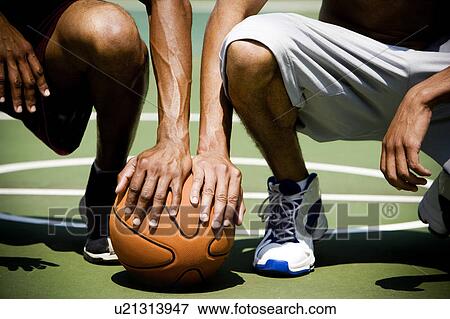 Stock Photo - Two African American kneeling side by side on an urban basketball court, close up. Fotosearch