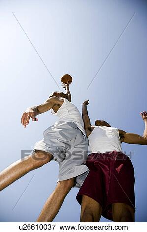 Stock Photo - Two African American men jumping for a basketball. Fotosearch