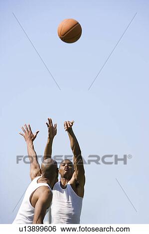 Stock Photograph - Two African American men jumping for a basketball. Fotosearch