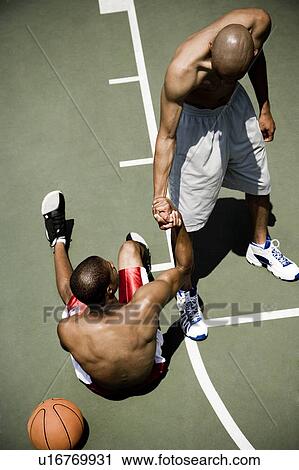 Stock Image - Two men playing on an outdoor basketball court . Fotosearch