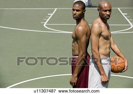 Stock Photo - Two Young African American standing back to back on an urban basketball court. Fotosearch