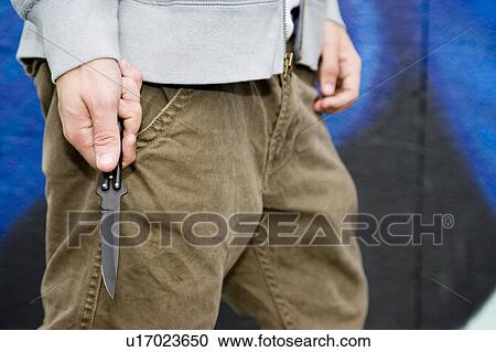 Stock Image - Close up of a young man holding a knife. Fotosearch
