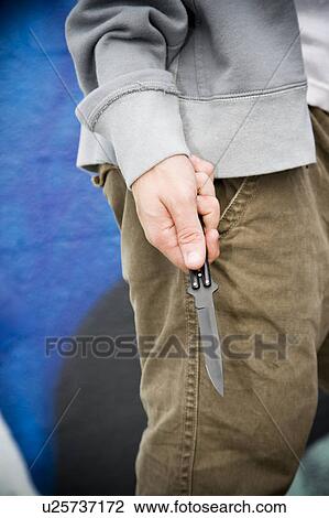 Stock Image - Close up of a young man holding a knife. Fotosearch