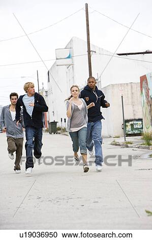 Stock Image - Group of teenagers running down an urban street . Fotosearch