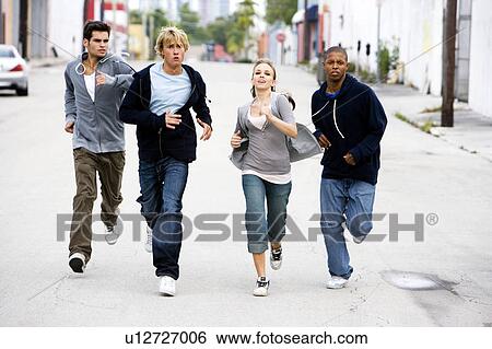 Stock Photograph - Group of teenagers running down an urban street . Fotosearch