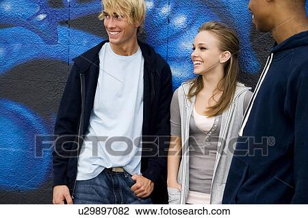 Stock Image - Portrait of a group of young friends hanging out in front of a graffiti covered wall . Fotosearch