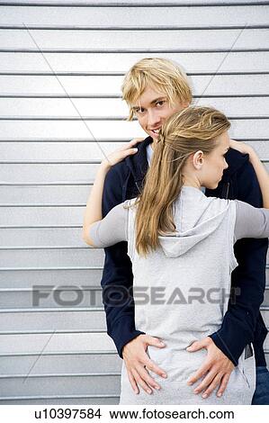 Picture - Portrait of a young couple leaning against a metallic wall . Fotosearch