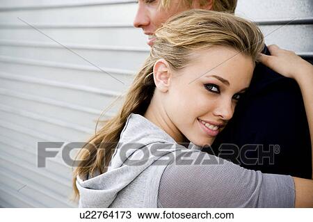 Stock Image - Portrait of a young couple leaning against a metallic wall . Fotosearch