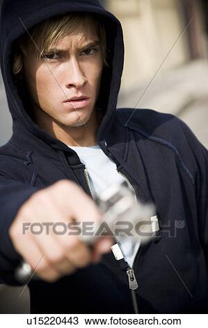 Stock Image - Portrait of a young man holding a gun . Fotosearch
