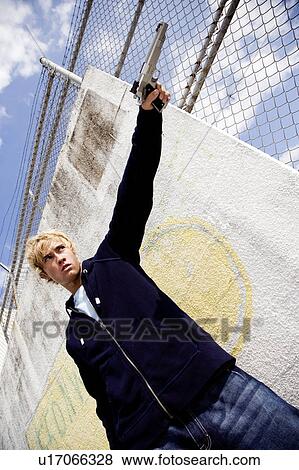 Stock Photo - Portrait of a young man holding a gun . Fotosearch