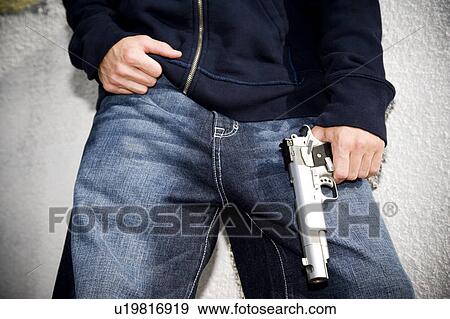 Stock Photo - Portrait of a young man holding a gun . Fotosearch