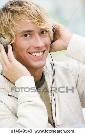 Portrait of a young man listening to music in front of a graffiti covered wall View Large Photo Image Stock Image - Portrait of a young man listening to music in front of a graffiti covered wall. Fotosearch
