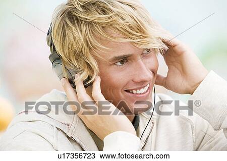 Portrait of a young man listening to music in front of a graffiti covered wall View Large Photo Image Stock Image - Portrait of a young man listening to music in front of a graffiti covered wall. Fotosearch