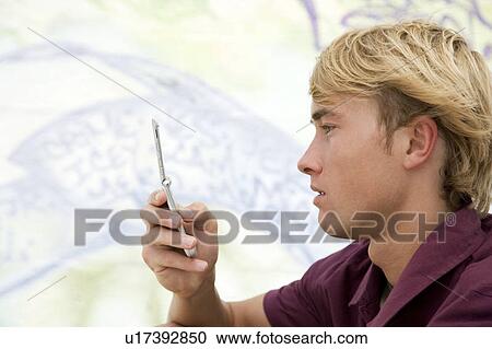 Portrait of a young man on a mobile phone in front of a graffiti covered wall View Large Photo Image Stock Image - Portrait of a young man on a mobile phone in front of a graffiti covered wall. Fotosearch