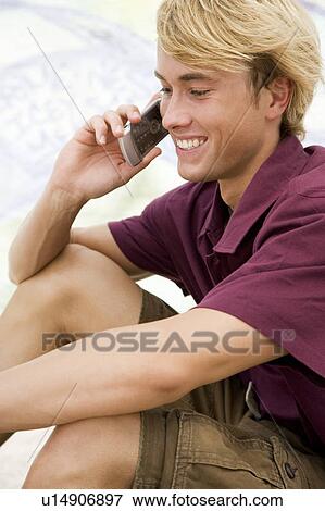 Stock Photo - Portrait of a young man on a mobile telephone in front of a graffiti covered wall. Fotosearch