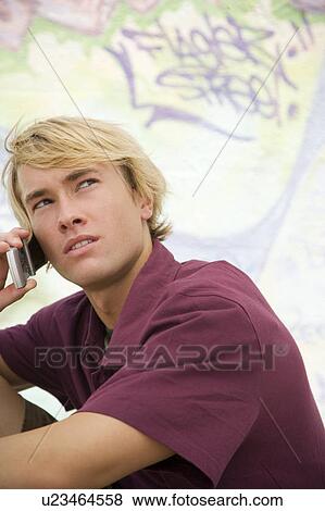 Portrait of a young man on a mobile telephone in front of a graffiti covered wallnn View Large Photo Image Stock Photo - Portrait of a young man on a mobile telephone in front of a graffiti covered wallnn. Fotosearch