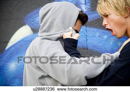 Stock Photograph - Two men fighting in front of a graffiti covered wall . Fotosearch