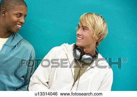Stock Photograph - Two young men leaning against a green painted wall . Fotosearch
