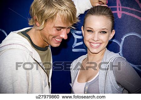 Stock Image - Young teenage couple in front of a graffiti covered wall. Fotosearch