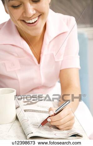 Stock Image - Diner waitress looking at the classified section of a newspaper . Fotosearch