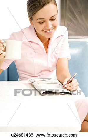 Stock Photograph - Diner waitress looking at the classified section of a newspaper . Fotosearch