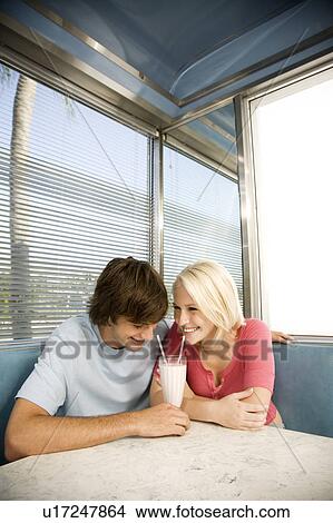 Portrait of a teenage couple sharing a milkshake in a diner View Large Photo Image Picture - Portrait of a teenage couple sharing a milkshake in a diner. Fotosearch