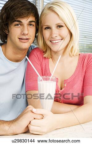 Portrait of a teenage couple sharing a milkshake in a diner View Large Photo Image Picture - Portrait of a teenage couple sharing a milkshake in a diner. Fotosearch