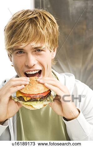 Teenage boy eating a large hamburger in a diner View Large Photo Image Stock Image - Teenage boy eating a large hamburger in a diner . Fotosearch