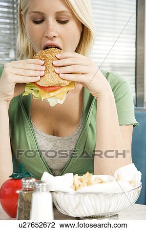 Teenage girl eating a hamburger in a diner View Large Photo Image Stock Image - Teenage girl eating a hamburger in a diner . Fotosearch
