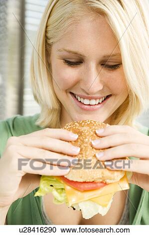 Stock Image - Teenage girl eating a hamburger in a diner . Fotosearch