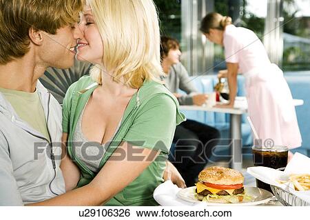 Stock Photograph - Young couple about to kiss, sitting in a diner . Fotosearch